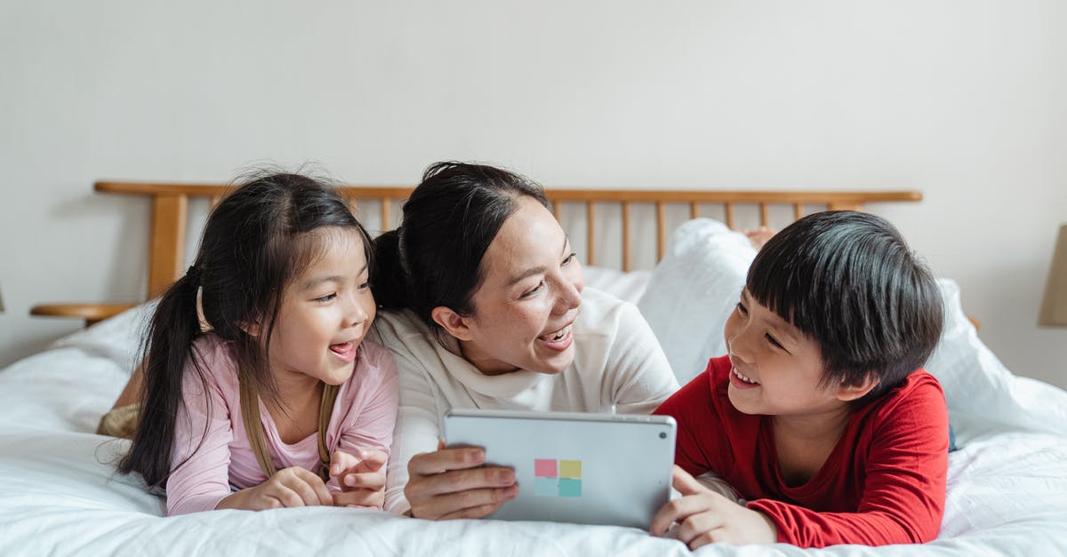 Does Lemond Bishop have other children? - Full body happy Asian female with smiling little children lying on belly in casual clothes on soft bed while using tablet in light apartment