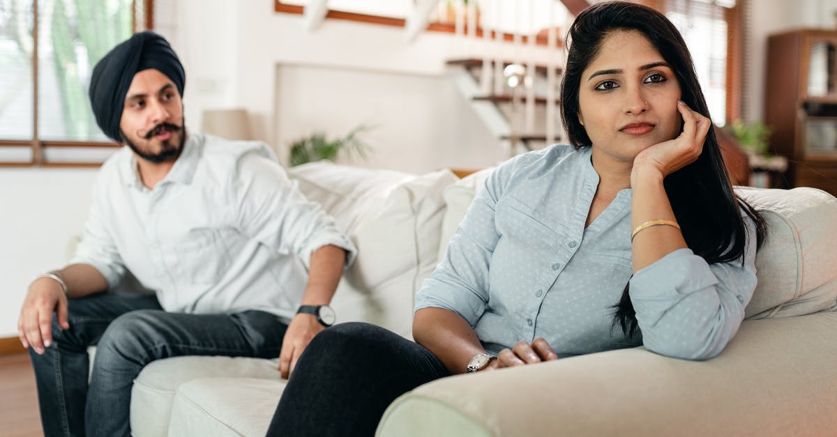 Does Louis still think about his wife? - Offended Indian woman sitting on sofa and looking sadly away while bearded husband trying to make peace after quarrel