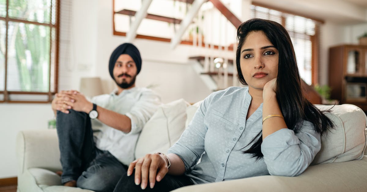 Does Louis still think about his wife? - Offended Indian woman sitting on sofa with husband on another end and looking away while having argument