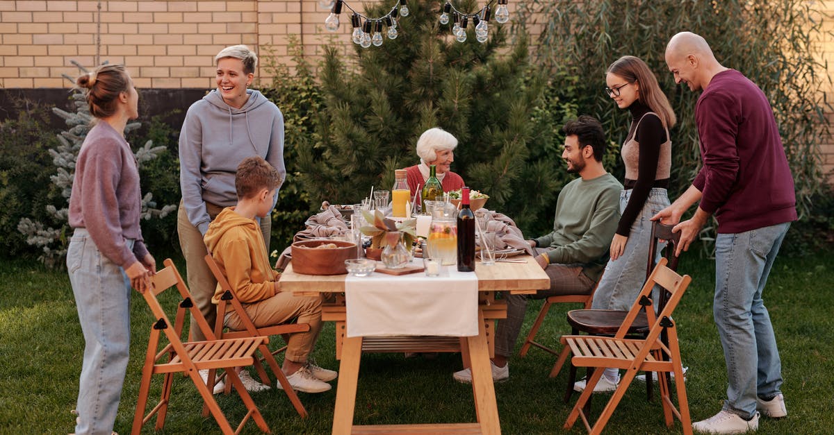 Does Malcolm Tucker have children? - Happy family members talking and sitting down to eat tasty food at big wooden table in backyard in daytime