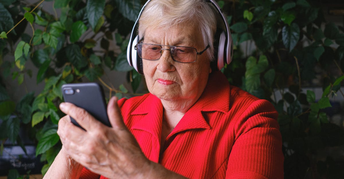 Does Mystique not age with time? - Focused aged woman browsing smartphone while listening to song