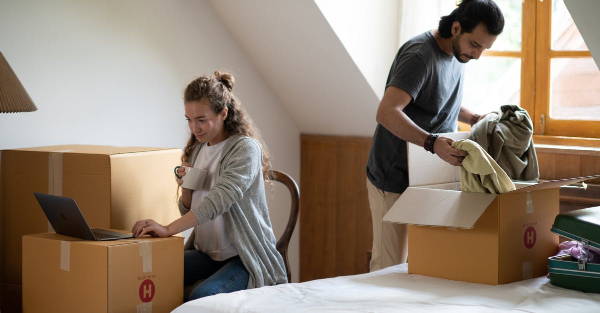Does Narcos use real corpses? - Pensive female surfing internet on netbook and drinking coffee while ethnic man unpacking belongings from cardboard box after moving into new attic style house