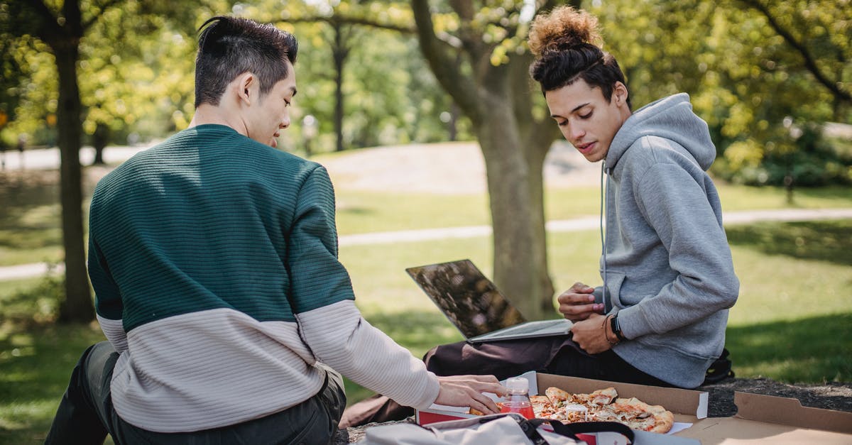 Does the assignment in Saving Private Ryan come impossibly fast? - Diverse students eating pizza while studying with laptop in park