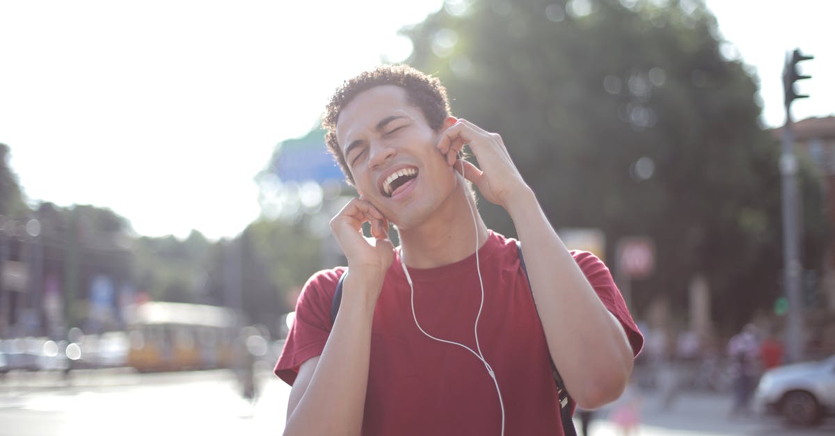 Does the Chinese song have any further relevance? - Delighted African American young male in casual wear enjoying songs in earphones on street and singing along loudly while standing in city with closed eyes