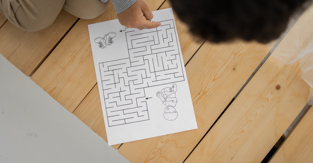 Does the wooden puzzle from Tomb Raider really exist? - Unrecognizable child solving labyrinth test printed on paper at home