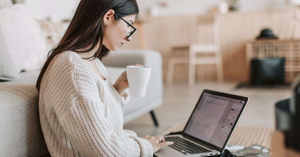 Does this device used to create suspense have a name? - Side view of female freelancer in warm sweater and eyeglasses drinking tea from white ceramic cup while sitting on floor near sofa with netbook on legs while creating document for remote work project