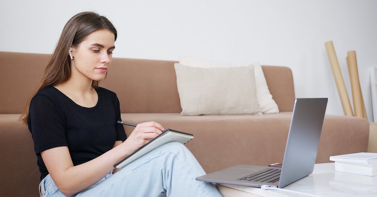 Dr. Brennan's Academic Position? - Glad young lady in jeans and black shirt writing down notes while attending online lesson and sitting on floor in cozy modern living room