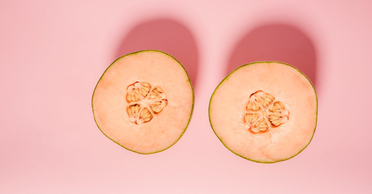 Ending of Half Light - Top view of ripe orange melon cut into halves for healthy diet placed on pink background in modern light studio