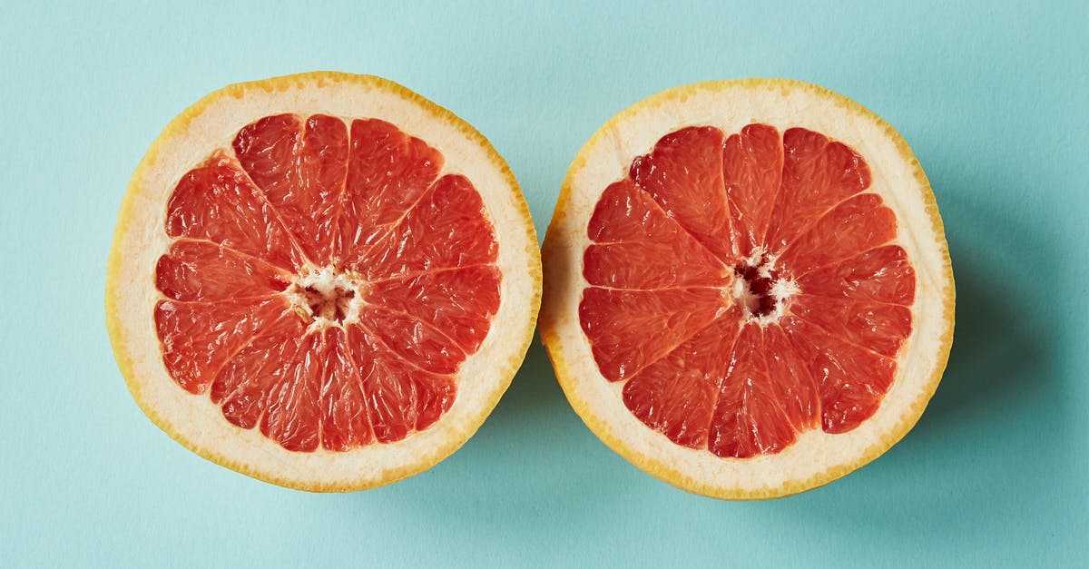 Ending of Half Light - From above of halves of bright orange juicy grapefruit placed on light blue background in studio