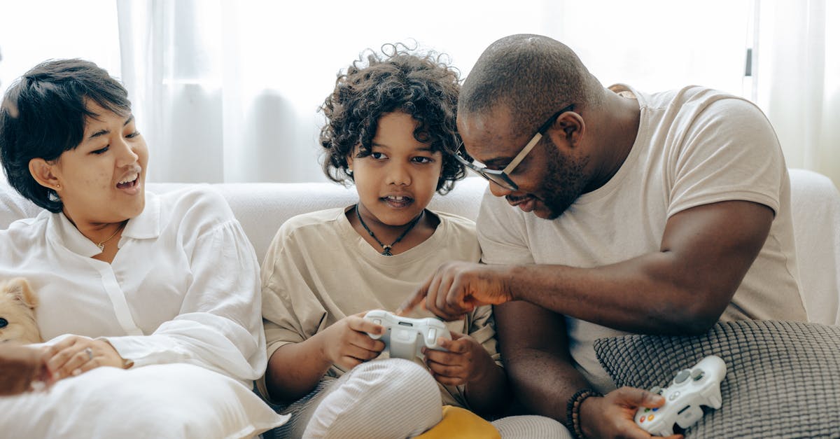 Explain the love triangle? - Concentrated black father pointing on joystick buttons explaining rules of playing to son while positive mother watching process