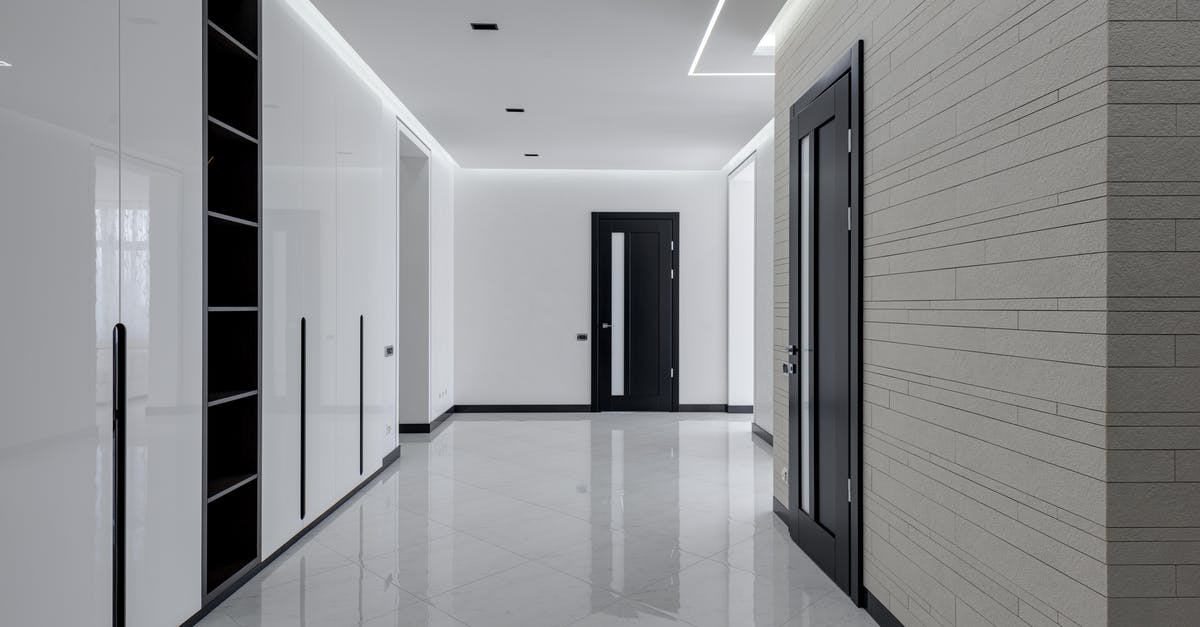 Explaining the door between the offices of House and Wilson - Wide corridor in modern house with white tiled walls and floor black wooden doors and shelves for storage built in wall