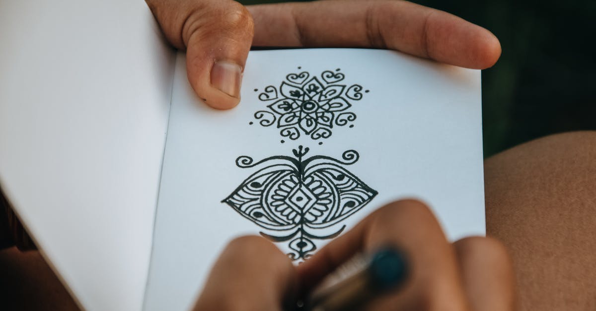 Extra meaning in "Panem" - Crop anonymous talented person creating difficult mehendi sketch in album with white sheets