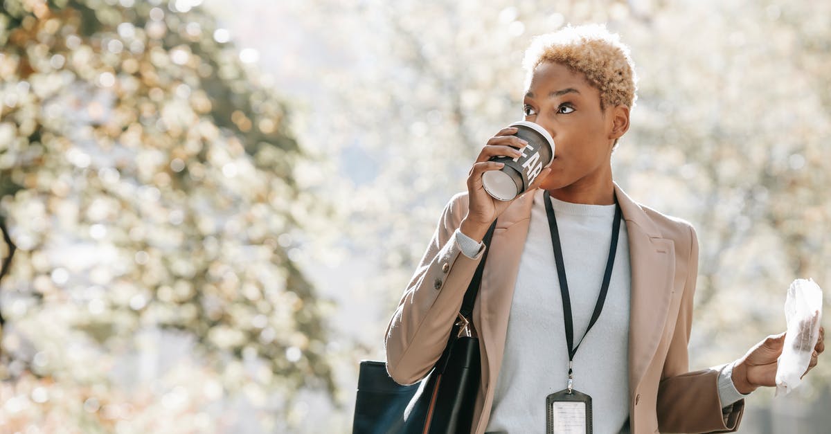 First appearance of going to past (time-travel) to change the present - Young African American businesswoman drinking takeaway beverage during coffee break in park
