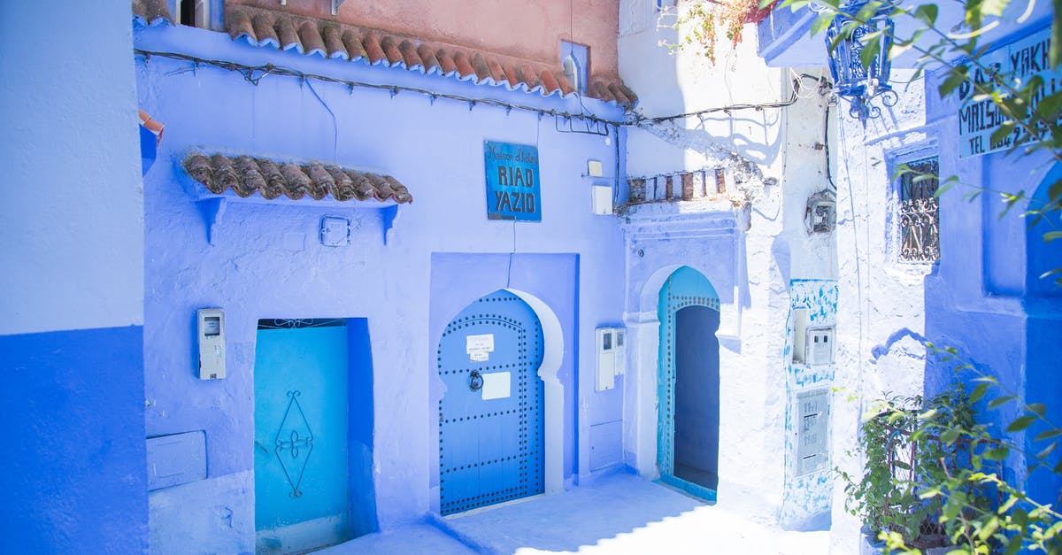 First color movie to use flickering and slamming door trope? - Blue exterior of house with doors located under sunlight on street with green plants in city of Morocco in summer