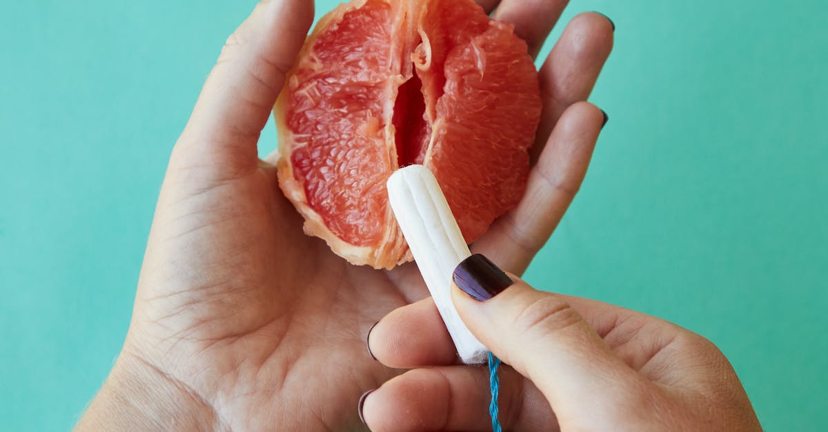 First example of "super-wealthy steal younger bodies for immortality" plot? - From above of crop anonymous female demonstrating on sliced ripe grapefruit correct use of tampon against blue background