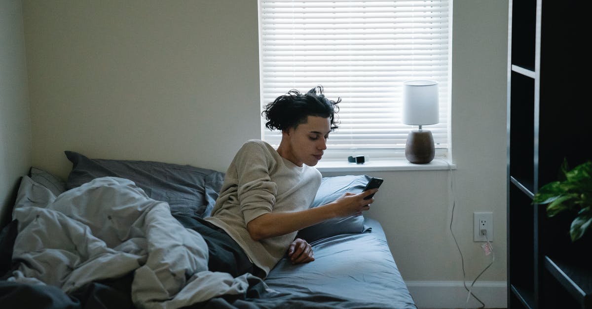 First use of on-screen text messages, like in Sherlock and House of Cards - Ethnic man chatting on smartphone in bed at home