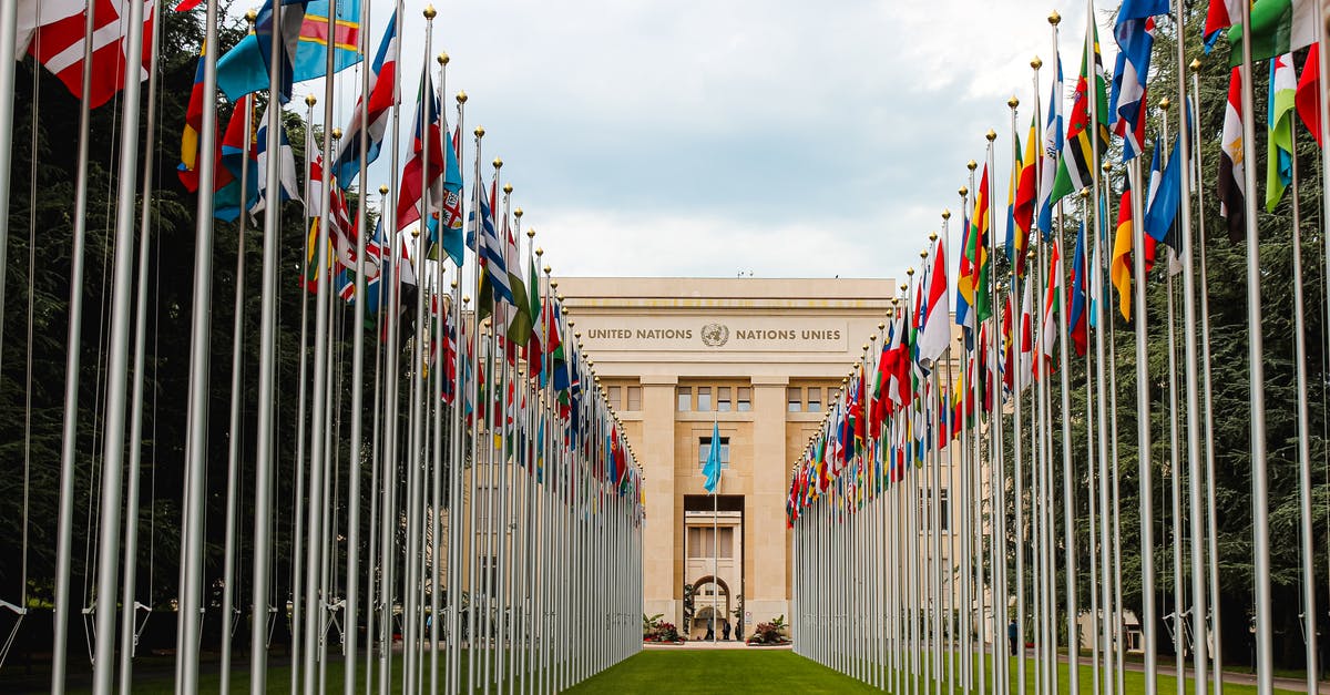 Flag in Around the World in Eighty Days - From below of various flags on flagpoles located in green park in front of entrance to the UN headquarters in Geneva