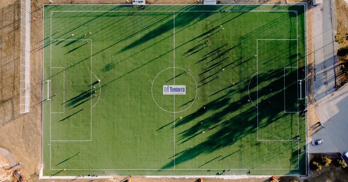 Game of Thrones Title Sequence - Aerial view of soccer field with anonymous sportspeople and shades against roadway on sunny day