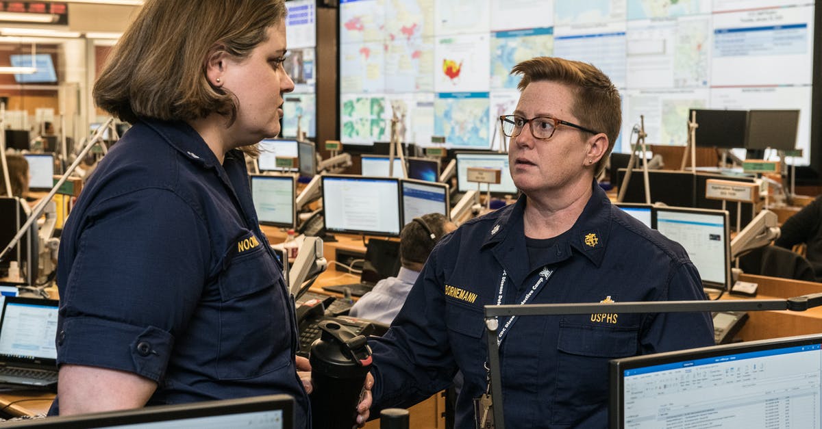 Has a streaming service original program ever reached 100 episodes? - Adult and mature serious female colleagues in uniforms talking and looking at each other while standing near tables with computers behind stand with maps in modern office