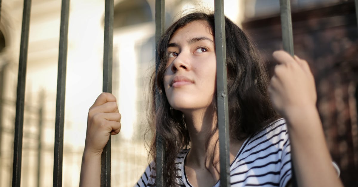 Have they really escaped from Alcatraz? - Sad isolated young woman looking away through fence with hope