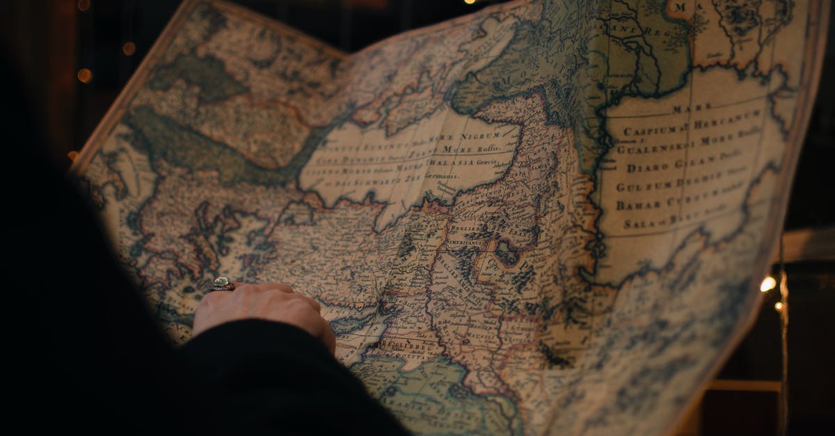 History of the World Pt. 2 - From behind anonymous person examining antique world map printed on large paper in blue colors in dark room