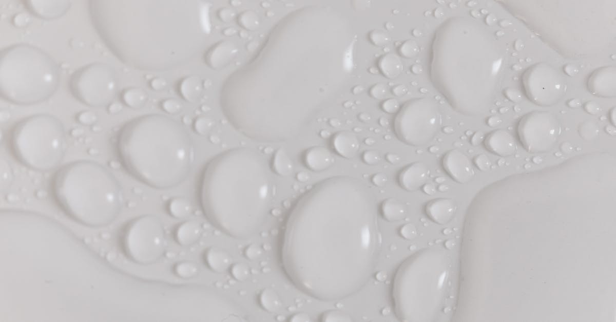 How are 3D still shots or "time stop" effects created? - Closeup top view of wet plain white background of droplet with translucent clean still water drops of different shapes and sizes