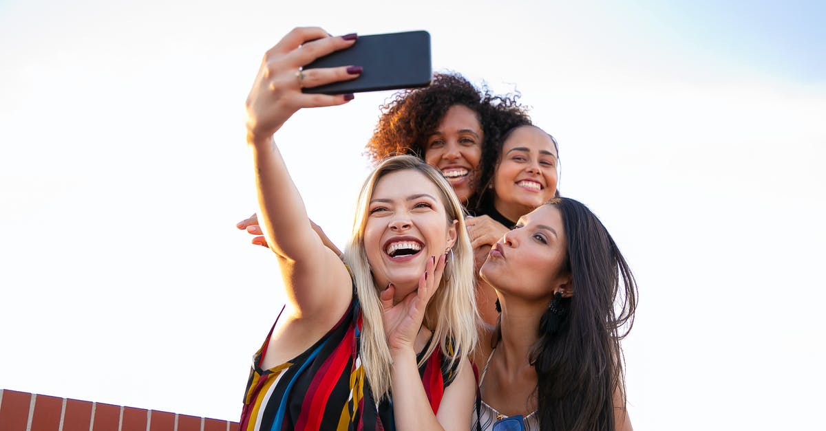 How are they captured? - Cheerful multiethnic girlfriends taking selfie on smartphone on sunny day
