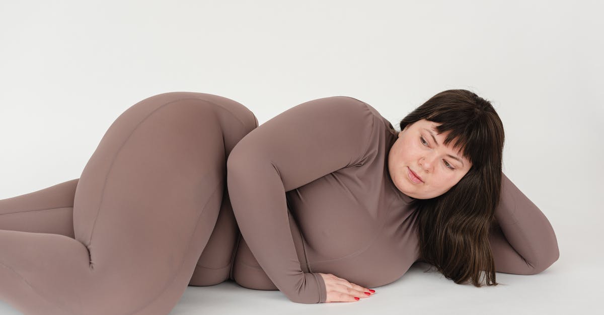 How can everyone in a large crowd hear the speaker from a long distance away? - High angle of serious plus size female with long hair leaning on hand while lying against white background