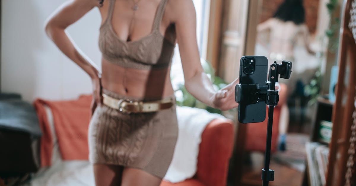 How can I tell whether or not a film has been broadcast on TV? - Crop unrecognizable ethnic female blogger demonstrating knitted outfit while setting up cellphone for shooting video for social media
