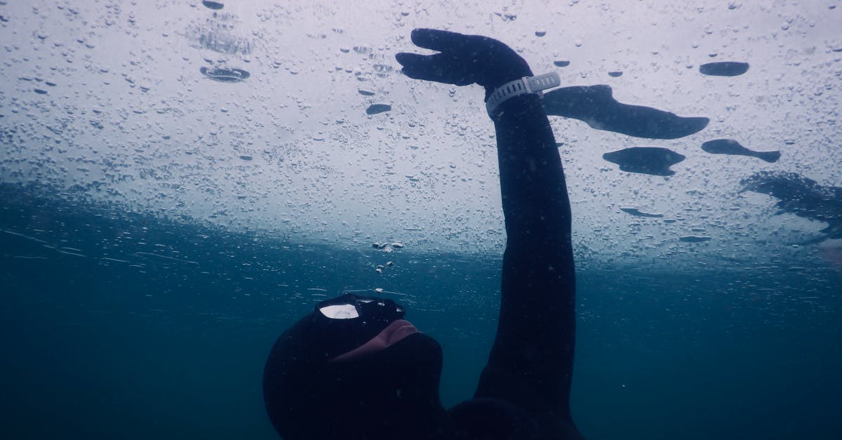 How can Kuzan (Aokiji) turn seawater into ice? - Anonymous diver in mask and wetsuit touching solid ice while swimming under seawater during freediving