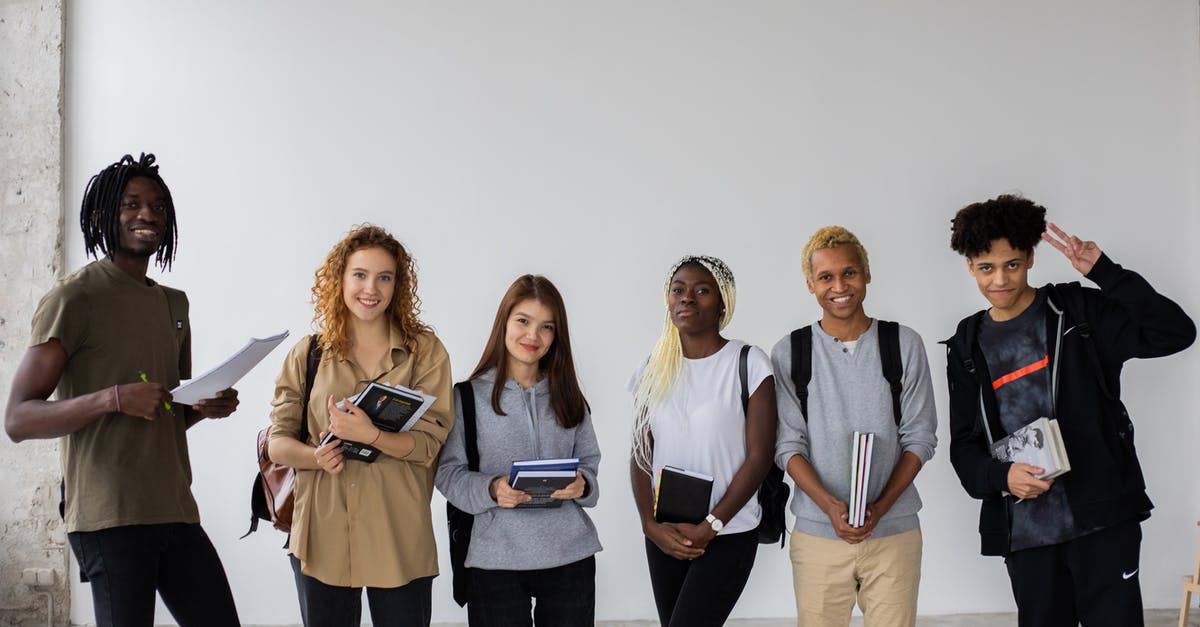How can Ted show a finger? - Group of smiling multiracial classmates standing with books and backpacks and smiling widely at camera