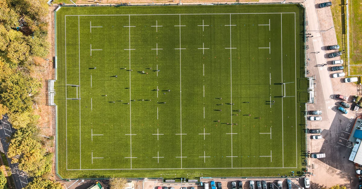 How Charlie and his team convert gold into car in such a short time span in Players? - Aerial view of unrecognizable people playing rugby on well groomed green field on sunny day in countryside