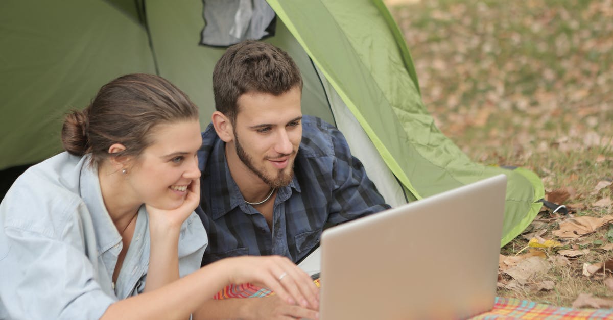 How come the Children of the Forest don't use dragonglass weapons? - Cheerful female and bearded male using laptop with touchpad while resting in tent at campsite