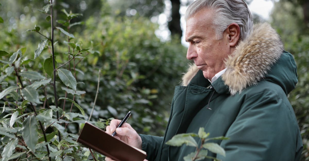 How come the scientist in the second planet is not super old? - Side view of aged gray haired male in warm outerwear writing with pen in notebook while standing in park