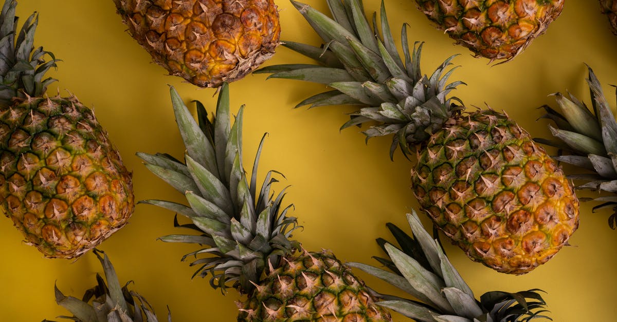 How could Captain Jack Sparrow die if he stole a crown from the island? - Top view of whole fresh pineapples with green leaves and brown skin arranged on yellow background in modern light studio