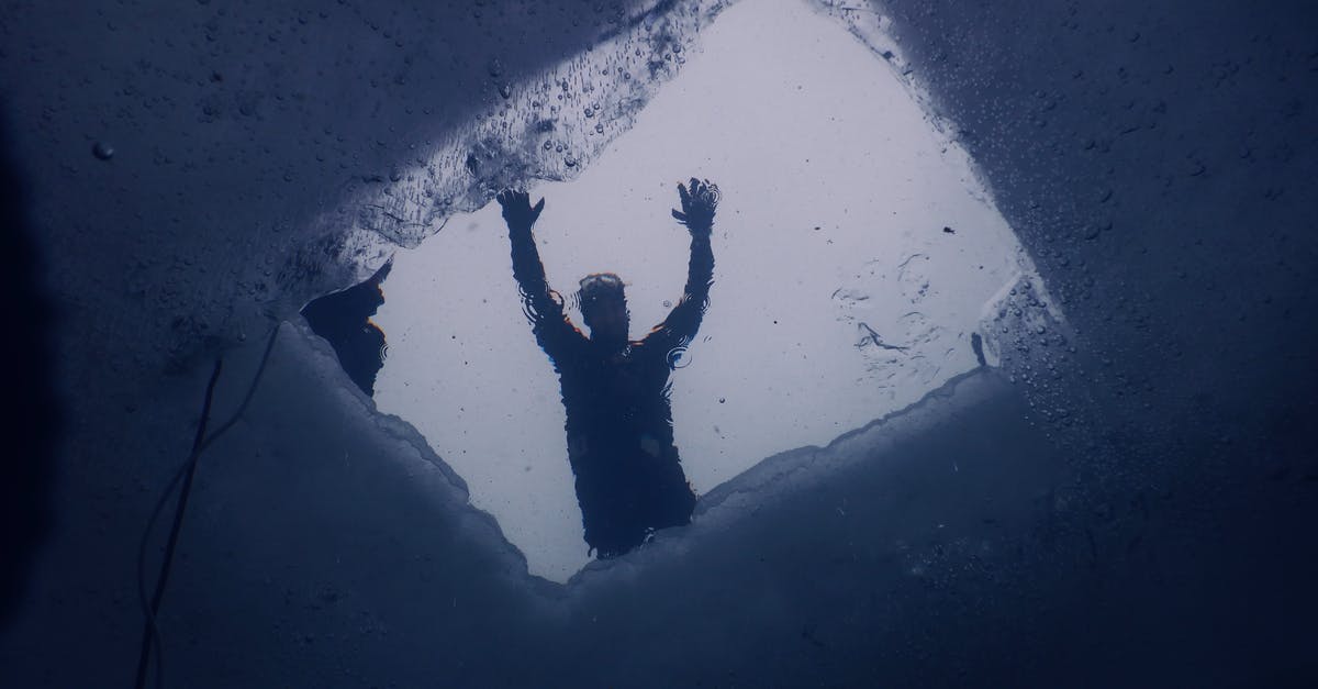 How deep is the hole in Sparta - Unrecognizable diver swimming under frozen water of sea