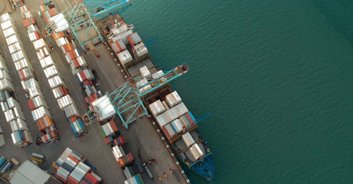 How detrimental was the initial hull breach by the shipping container for the boat's ultimate fate? - Top view of harbor with containers and cargo ships located near calm rippling sea water