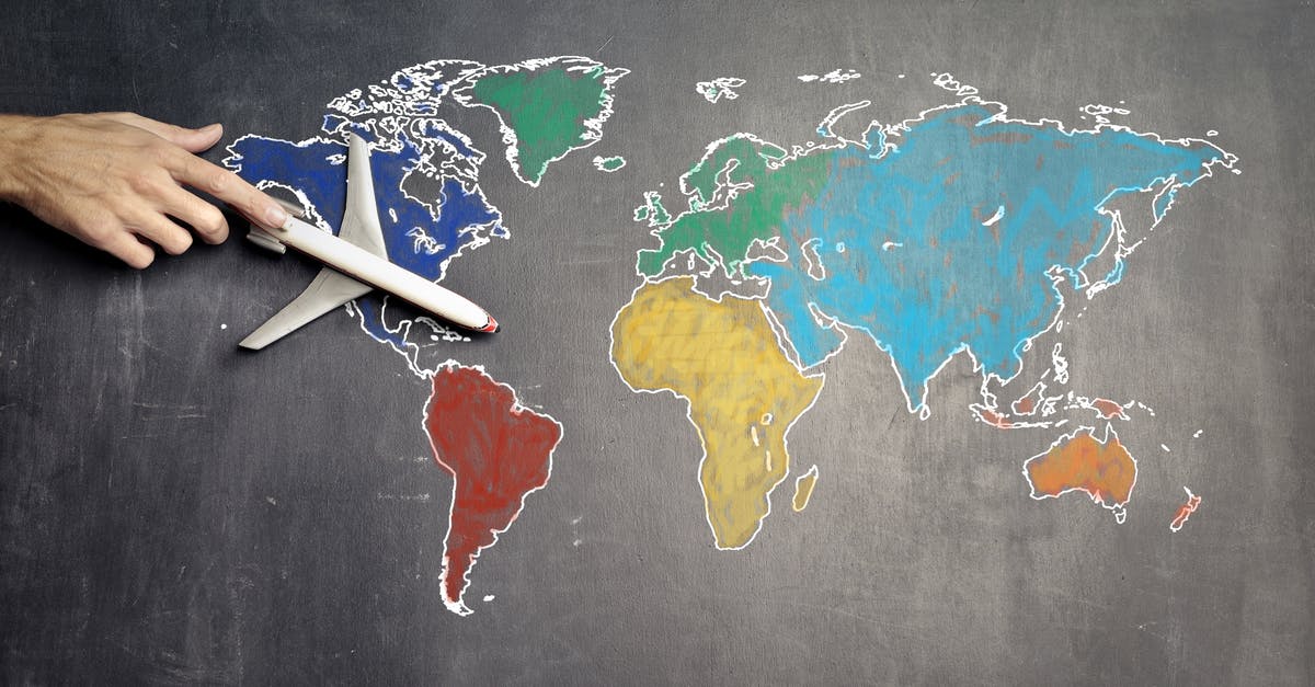 How did a zombie get onto the plane in World War Z? - Top view of crop anonymous person holding toy airplane on colorful world map drawn on chalkboard