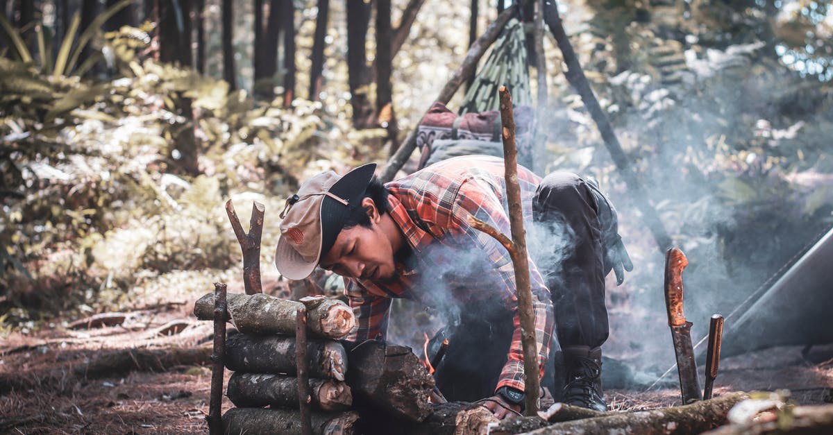 How did Carl survive the eyeshot? - Ethnic man preparing bonfire in forest during expedition