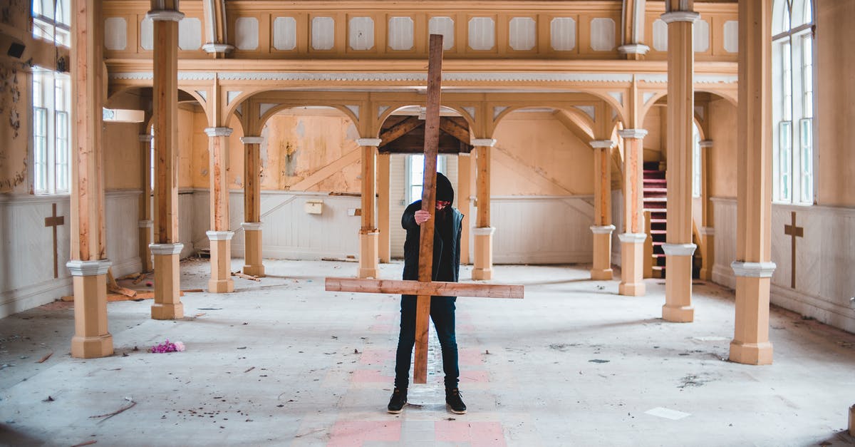 How did Christian Wolff kill this guy without hurting himself? - Full body of unrecognizable male stalker in black clothing carrying overturned wooden Christian cross while walking through abandoned church