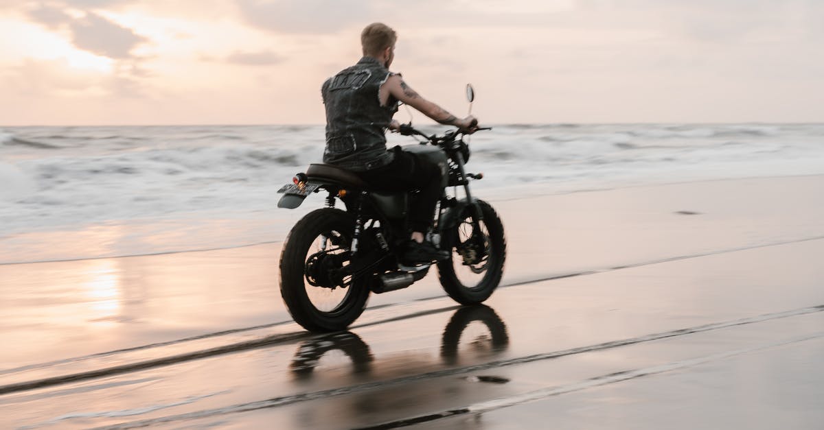 How did Darth Maul trace the Queen/Jedi back to Tatooine? - Back view of anonymous tattooed biker in sleeveless shirt riding motorcycle on wet sand with traces near sea with foamy waves under cloudy sky at sunset