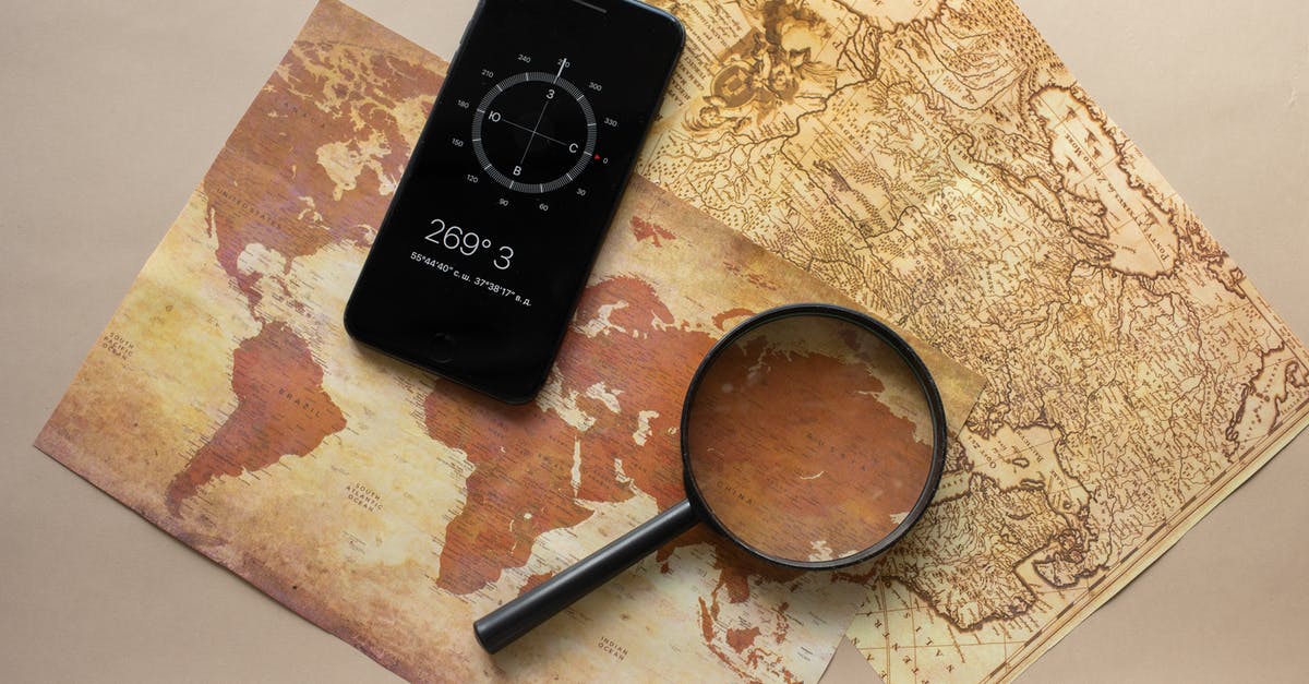 How did Fawkes find the Chamber of Secrets? - Top view of magnifying glass and cellphone with compass with coordinates placed on paper maps on beige background in light room