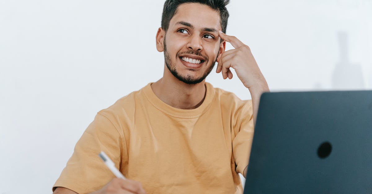 How did Landa think his plan would work? - Smiling young bearded Hispanic male entrepreneur thinking over new ideas for startup project and looking away dreamily while working at table with laptop and taking notes in notebook