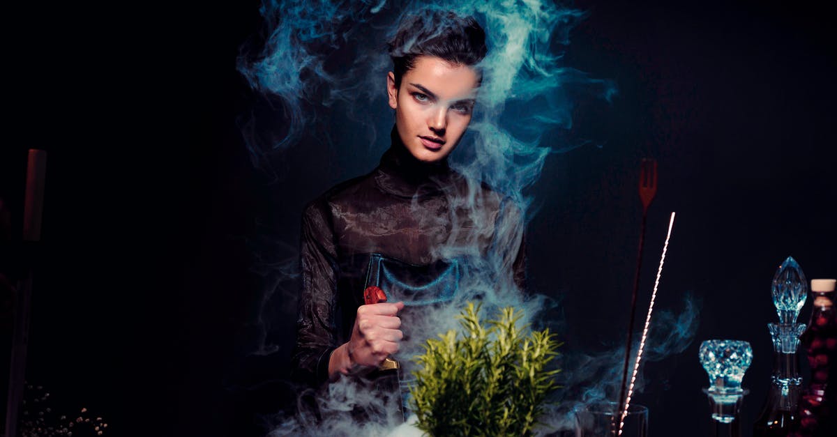 How did Lark prepare this? - Graceful young female alchemist with knife in hand in black outfit preparing potion from various herbs among smoke in dark room