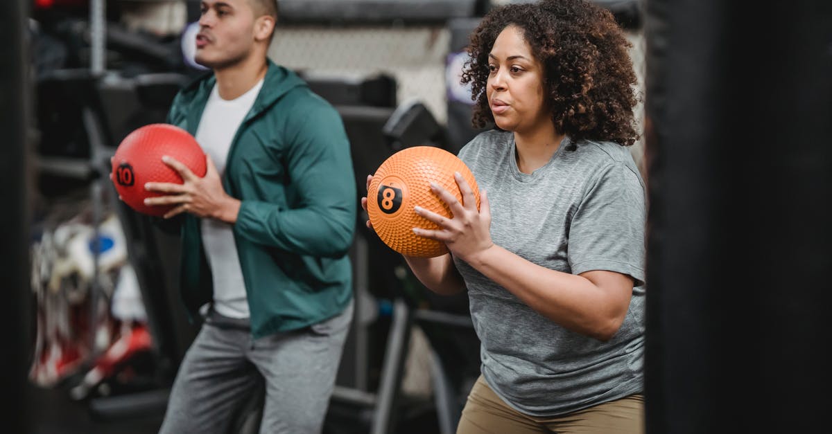 How did Seth Powers keep the ball spinning? - Concentrated young diverse trainer and athlete exercising with medicine balls in gym