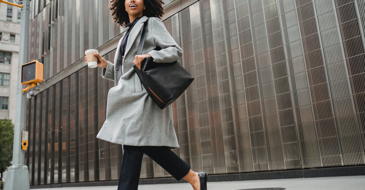 How did the model 101 know when and where Legion terminators were going to appear? - Low angle of confident African American female in trendy outfit with bag holding coffee while crossing road in downtown of city