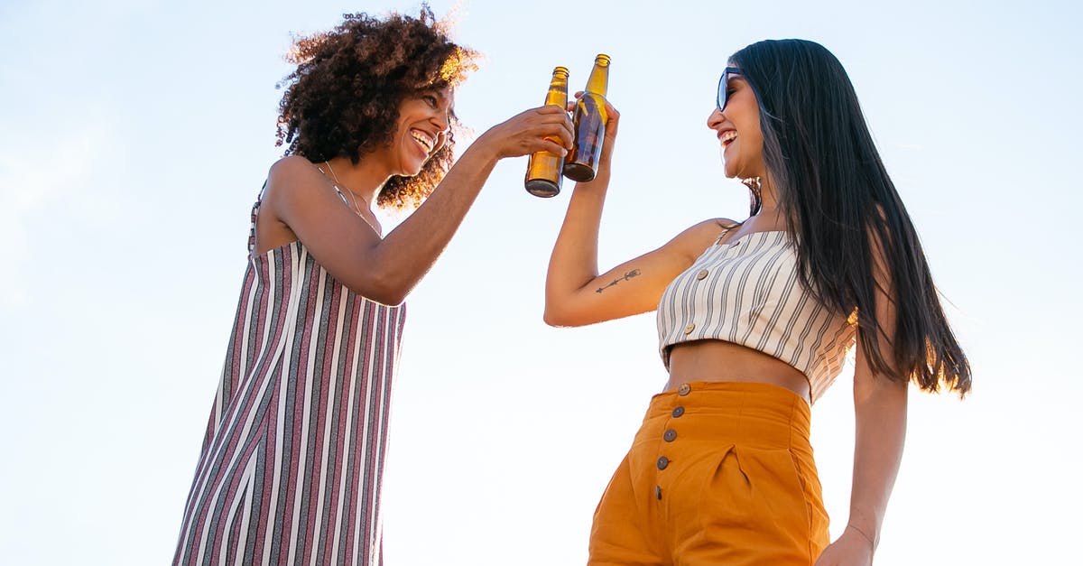 How did the other Brainiac 5 know about the bottle? - Low angle of delighted multiracial female friends toasting with bottles of beer while laughing together during party