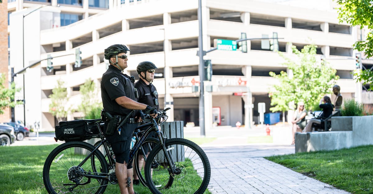 How did the police department survive, and why were they allowed to? - Side view full length serious bicycle patrol policemen in uniforms and helmets standing on city lawn