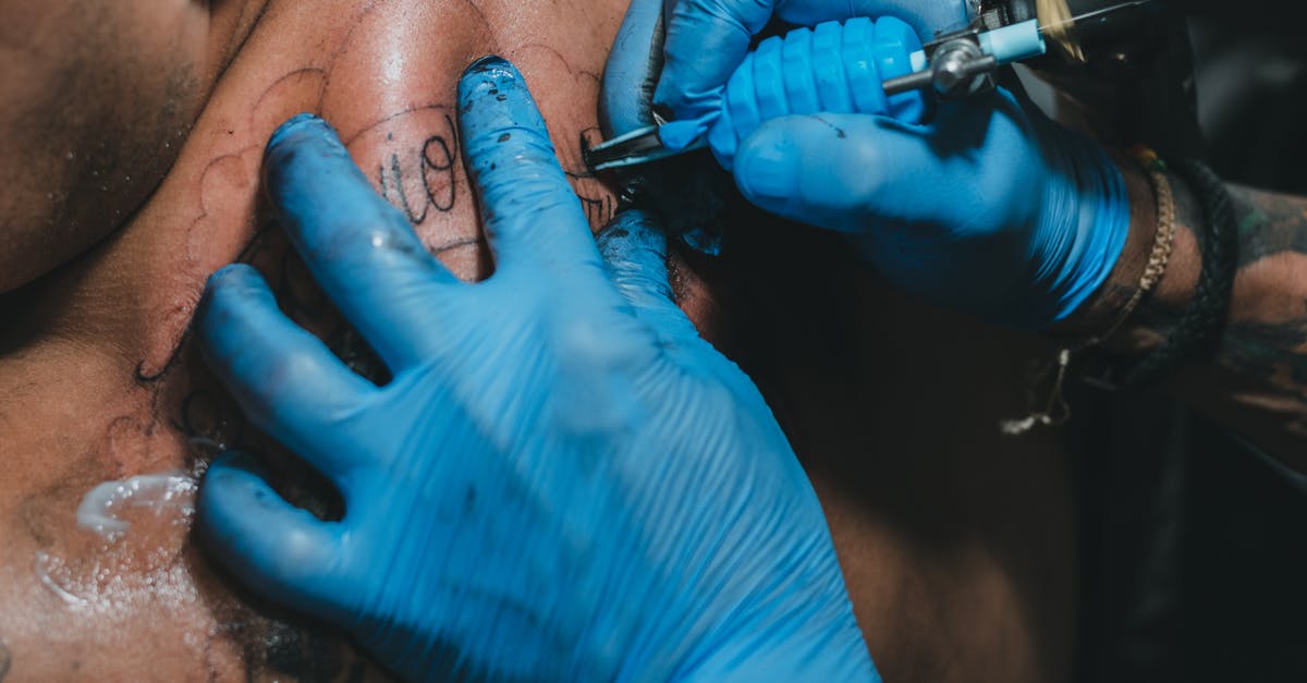 How did they make these gun sound effects from the 1970's? - High angle hands of anonymous tattooist in blue gloves using professional tool to make tattoo on back of client in salon