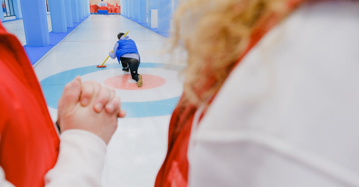 How did Thor know the Power stone was in play? - Sportive team in red vests standing and looking at unrecognizable sportsman in blue vest sliding with stone and broom in hand while playing curling on ice rink